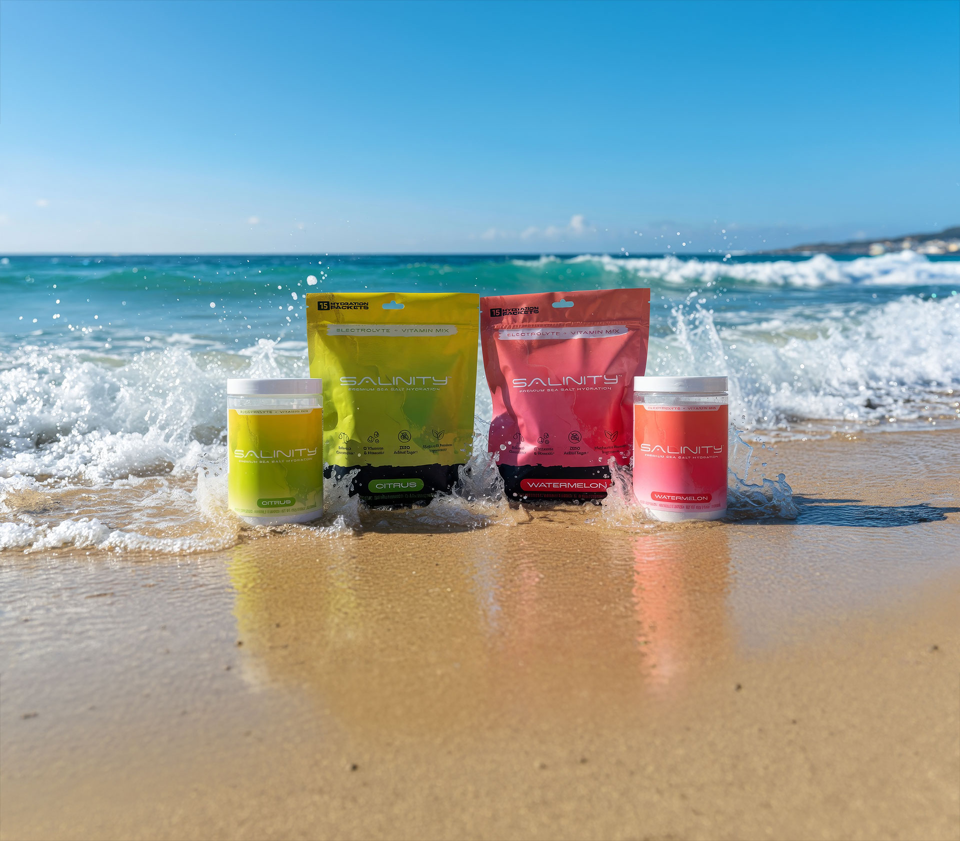 Salinity Citrus and Watermelon pouches and tubs standing on wet sand as a wave breaks behind them